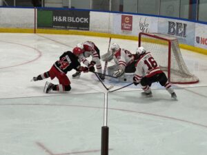 Lumber Kings player on his knees shoots the puck at the Nepean Raiders net.